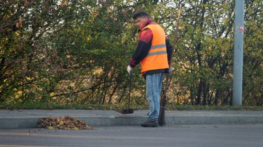 Brest, Belarus - 18 Ekim 2019: hademe asfalttan dökülen yaprakları ve enkazı temizliyor.