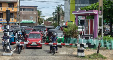 Sri Lanka, Colombo-1 Aralık 2019: sıradan insanların basit hayatları. Büyük şehirde toplumun günlük yaşamını aç. Tut-tuk ve motosikletler demiryolu geçidinde birikti.