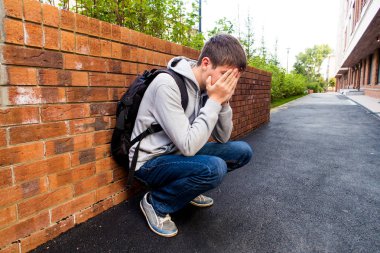 Üzgün genç adam şehir sokakta oturup