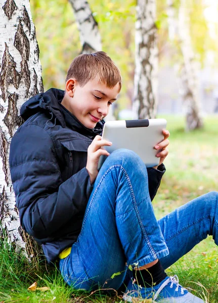 Çocuk Sonbahar Parkta Bir Tablet Bilgisayar Ile — Stok fotoğraf