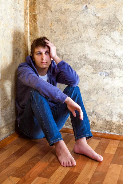 古い壁によって床の隅に悲しい若い男 — ストック写真