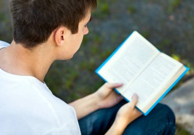 Genç adam şehir sokak bir kitap okumak