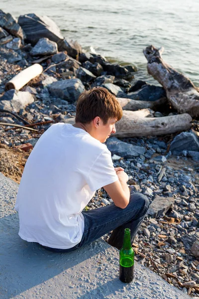 Sad Young Man Met Een Biertje Zitten Aan Zee — Stockfoto