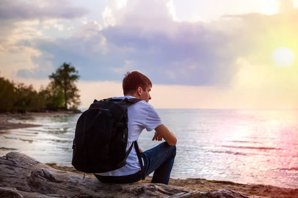 Nadenkend Young Man Oever Bij Zonsondergang — Stockfoto