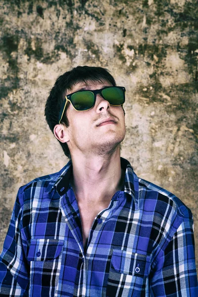 Genç adam bir güneş gözlüğü tarafından eski duvar arka plan fotoğrafı tonda