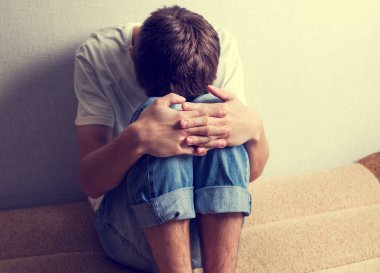 Fotoğraf duvar tarafından kanepede üzgün gencin tonda