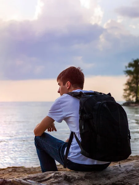 Junger Mann Mit Rucksack Sitzt Auf Baumstamm Meer — Stockfoto