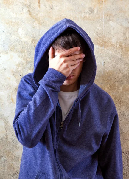 Eski duvar tarafından Hoodie üzgün genç adam