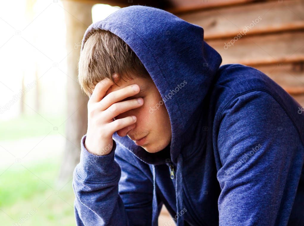Sad Young Man in a Hoodie near the House