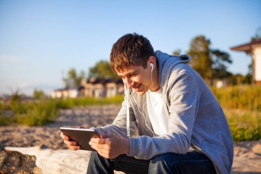 Genç adam bir Tablet bilgisayar ve kulaklık açık