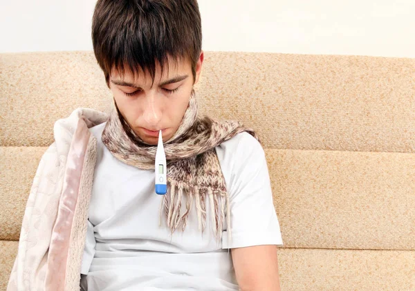 Evde Kanepede Tıbbi Bir Termometre Ile Yorgun Genç Adam — Stok fotoğraf