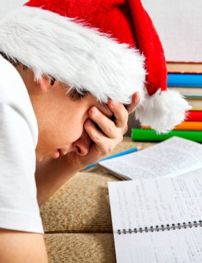 Noel Baba şapkası kanepede ödev kitapları ile yorgun öğrenci