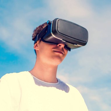 Fotoğraf gökyüzü arka plan üzerinde sanal gerçeklik bardaklarda genç adamın tonda