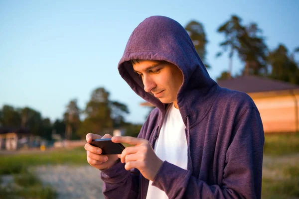 Mladý Muž Hledá Telefonu Pozadí Přírody — Stock fotografie