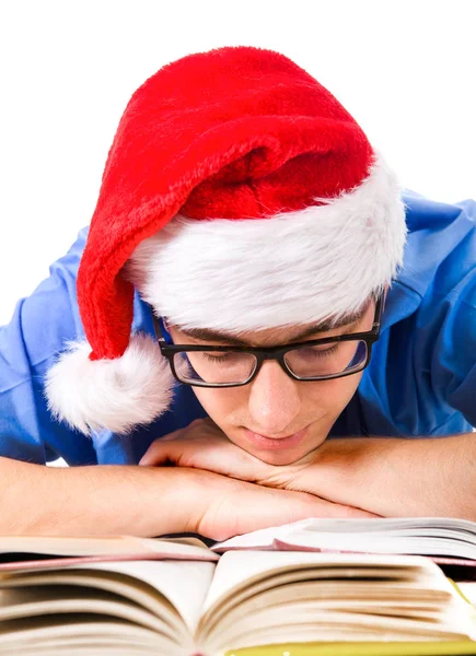 在圣诞老人的帽子上的疲惫和无聊的学生在学校书桌查出的白色背景 — 图库照片