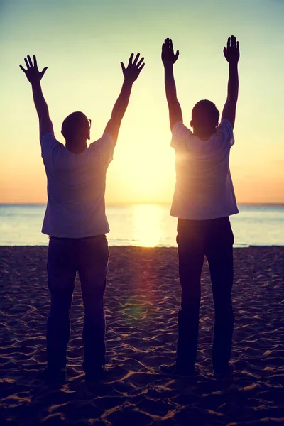 两个男人剪影的色调照片与手在日落背景 — 图库照片