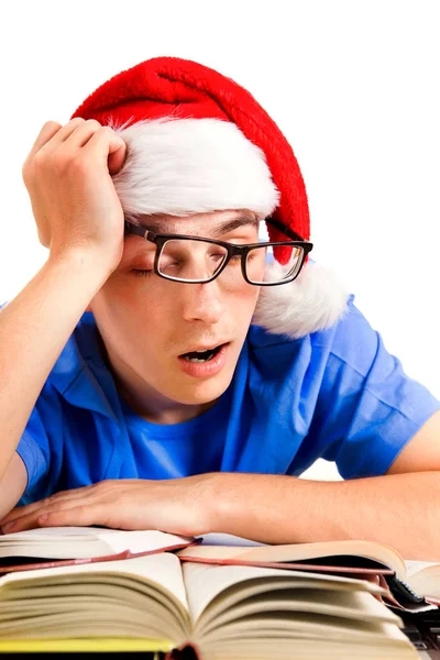 在圣诞老人的帽子上的疲惫的年轻男子在学校办公桌查出的白色背景 — 图库照片
