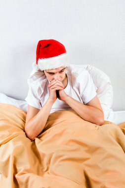 Noel Baba şapkası yatakta üzgün genç adam