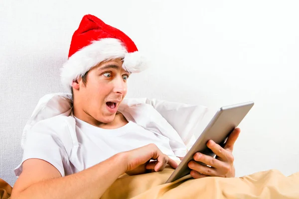 Joven Sorprendido Santa Sombrero Con Una Tablet Computer Cama — Foto de Stock