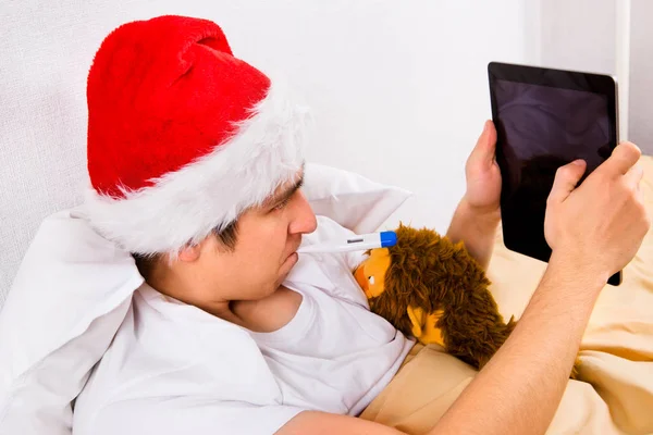Νεαρός Άνδρας Καπέλο Santa Ένα Θερμόμετρο Και Έναν Υπολογιστή Tablet — Φωτογραφία Αρχείου