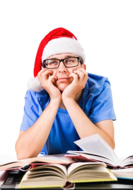 Noel Baba'nın şapkalı beyaz arka plan üzerinde izole okul masasında yorgun ve bıkkın öğrenci