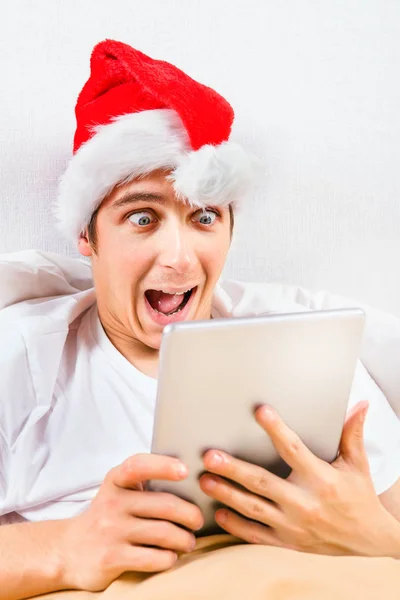 Έκπληκτος Νεαρός Καπέλο Santa Έναν Υπολογιστή Tablet Στο Κρεβάτι — Φωτογραφία Αρχείου