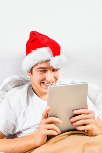 Felice Giovane Uomo Santa Hat Con Computer Tablet Nel Letto — Foto Stock