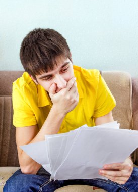 Üzgün genç adam kanepede belgelerle