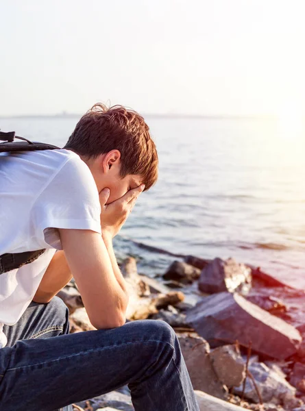 悲しい海の背景に座る若い男 — ストック写真