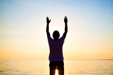 Fotoğraf adam silueti deniz arka plan üzerinde günbatımında dua tonda