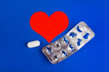 Bir hap mavi Kağıt arka plan üzerinde kırmızı kalp şekli