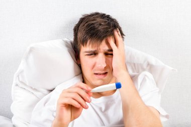 Evde yatakta bir termometre ile acı genç adam