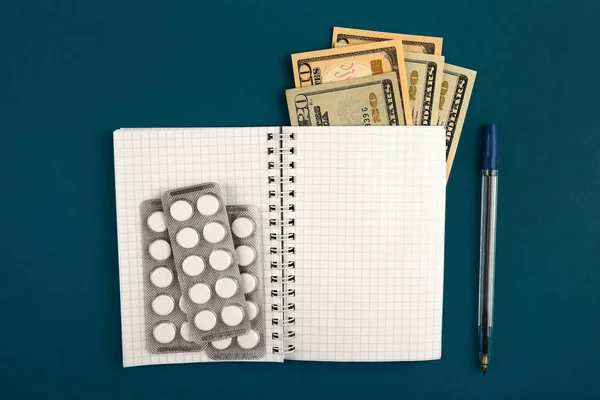Writing Pad with a Money and the Pills on the Green Paper closeup