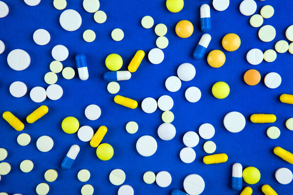 Scattering Pills on the Blue Paper Background closeup