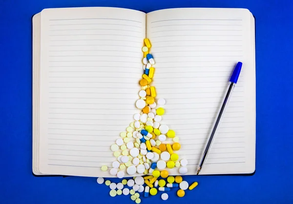 Blank Writing Pad and Scattering Pills on the Blue Paper Background closeup