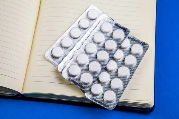 Writing Pad and the Pills on the Blue Paper closeup