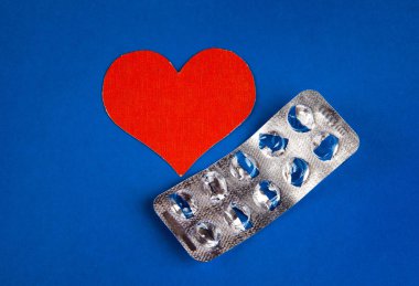 Bir hap mavi Kağıt arka plan üzerinde kırmızı kalp şekli