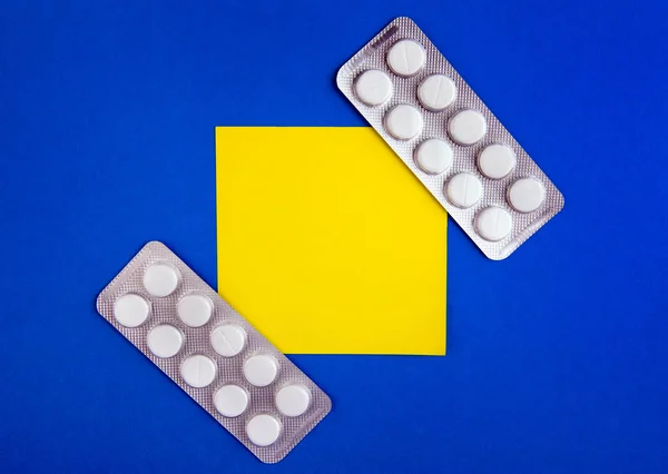 薬と青の段ボール背景に空の黄色い紙 — ストック写真