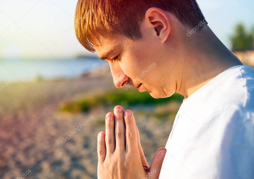 Young Man Praying on the Nature Background closeup