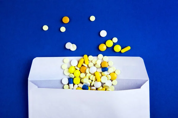 Pills with an Envelope on the Blue Paper Background closeup