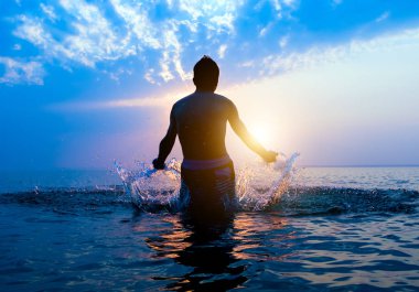 Mutlu adam siluet günbatımı arka plan üzerinde suda sıçraması ile