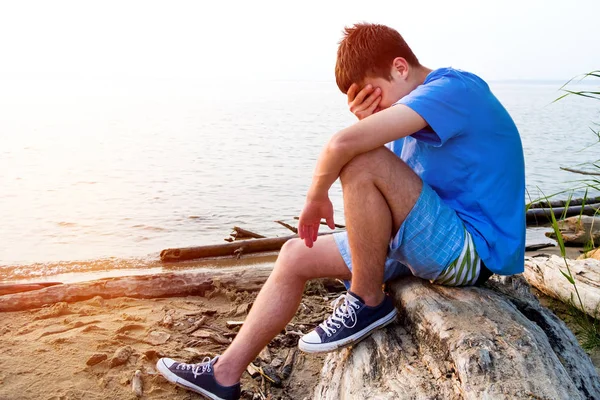 Sad Young Man Zitten Het Logboek Aan Zee — Stockfoto