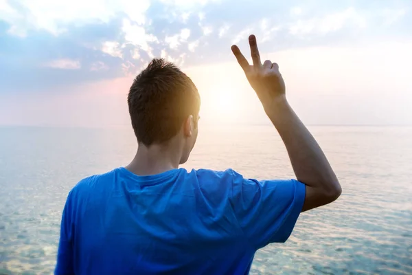 Happy Man with Victory Gesture on the Sea Background