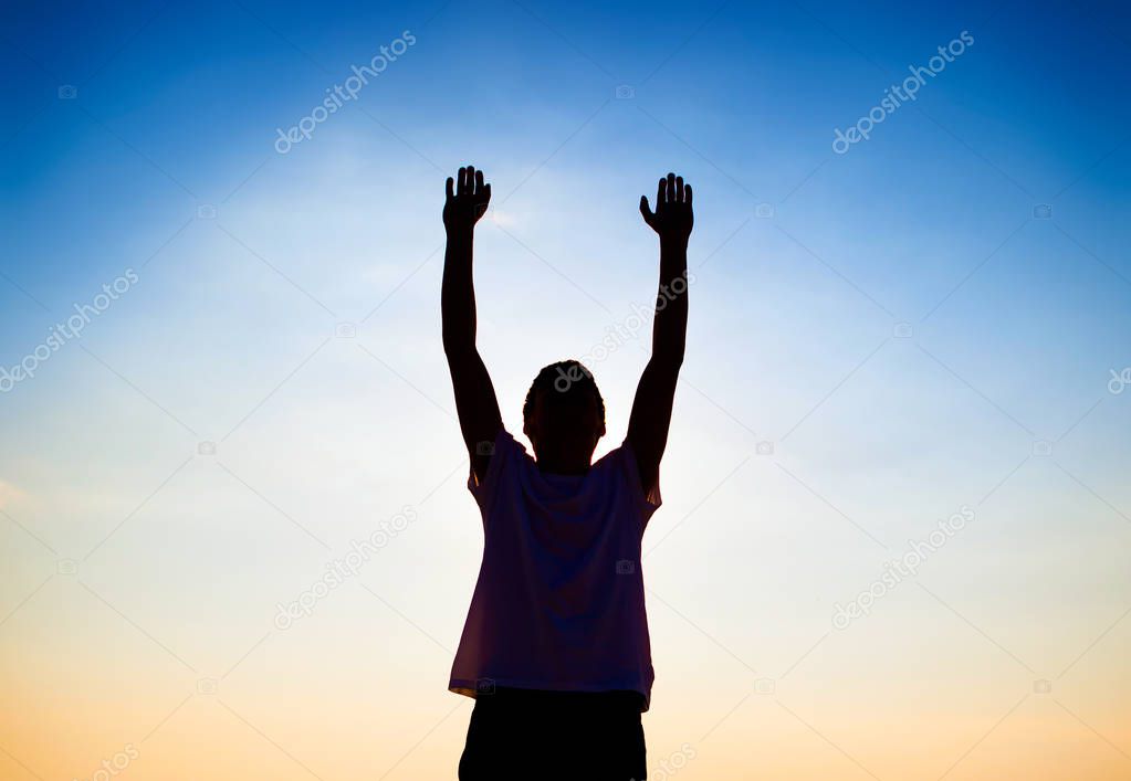 Silhouette of a Man with Hands Up on the Evening Sky Background