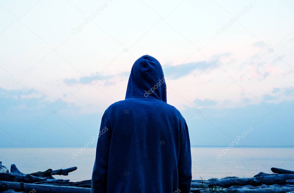 Silhouette of a Man in a Hoodie on the Sea Background