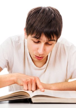 Genç adam okul masanın üzerinde beyaz arka plan üzerine bir kitap okumak