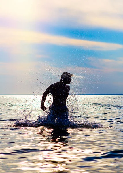 在日落背景的水飞溅的人剪影 — 图库照片