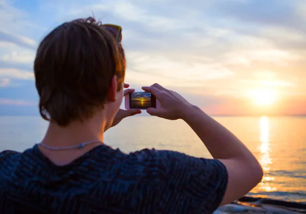 若い男は 海で携帯電話で写真を撮る — ストック写真
