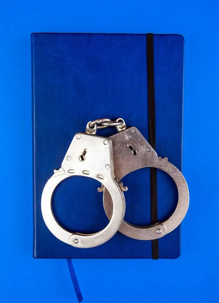 Book Handcuffs Blue Paper Background Closeup — Stock Photo, Image