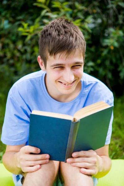 快乐的年轻人读了一本关于夏天草原的书 — 图库照片